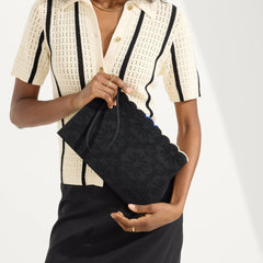 hover | The Wristlet in Black Carnation held by a model shown from the front.