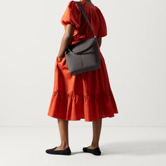 The Mini Zip Bucket in Ink and Ivory, carried over the shoulder of a female model, shown from the back.