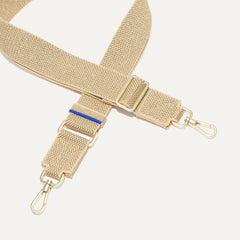 A close-up of The Crossbody Strap in Gold Dust, focusing on the end snap hooks and sliding buckle.