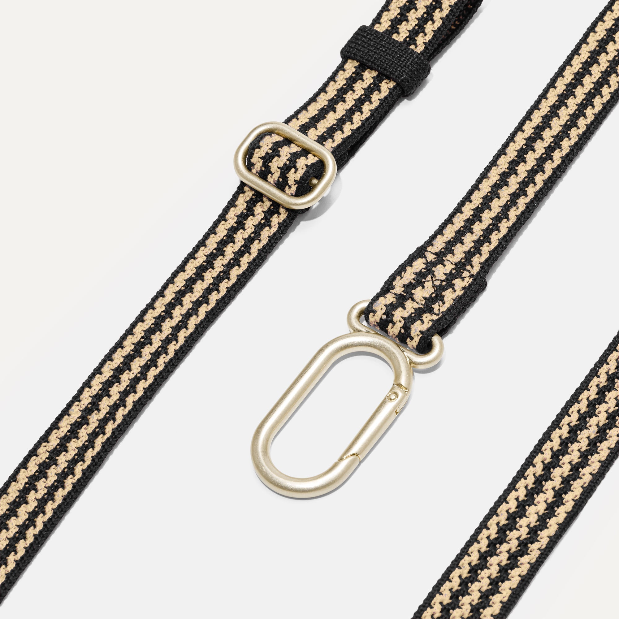 Close up of the adjustable, detachable strap of The Casual Sling in Toffee Stripe. 