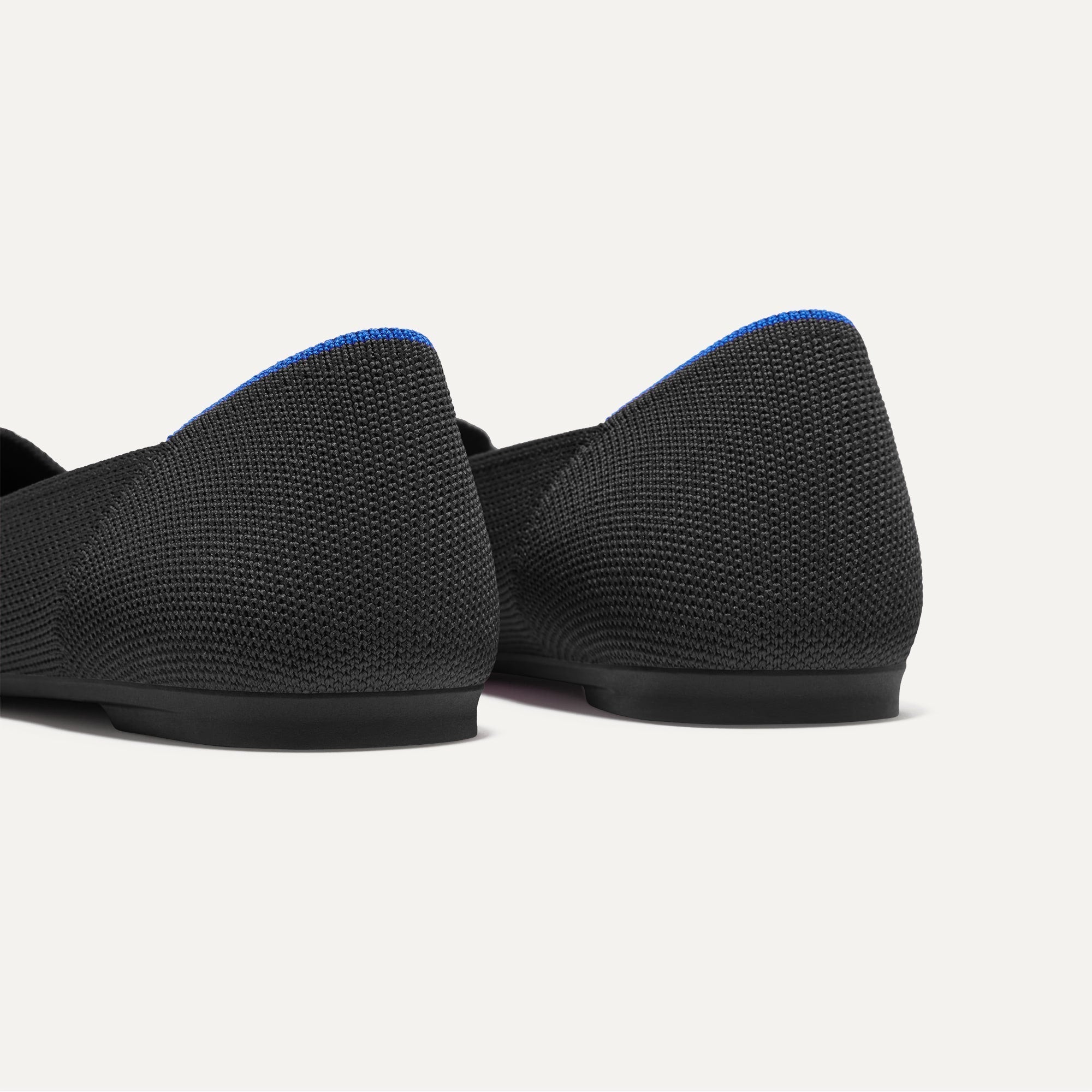 Close up of the heel of The Petal Point II in Black, with Rothy's signature blue halo.